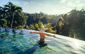 sexy woman enjoying the sun at infinity summer swimming pool at luxurious resort